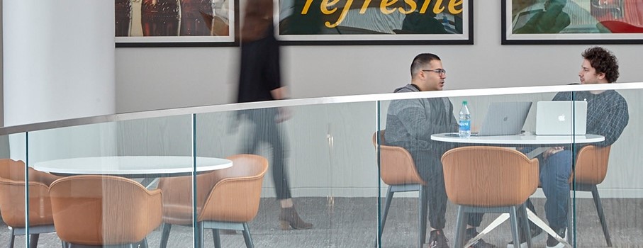 Colleagues sit and talk at Coca-Cola as another passes by