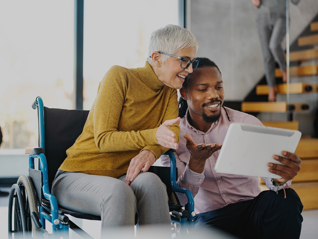 A woman in a wheelchair reviews a document with a man kneeling beside her