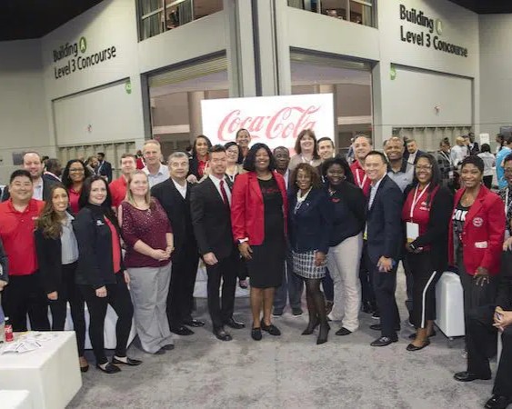 Dozens of Coca-Cola employees together for a photo in a convention hall